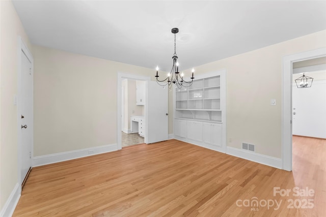90 Pinewood Rd, Granite Falls, NC 28630 - unfurnished dining area featuring a chandelier, light wood-type flooring, baseboards, and built in shelves