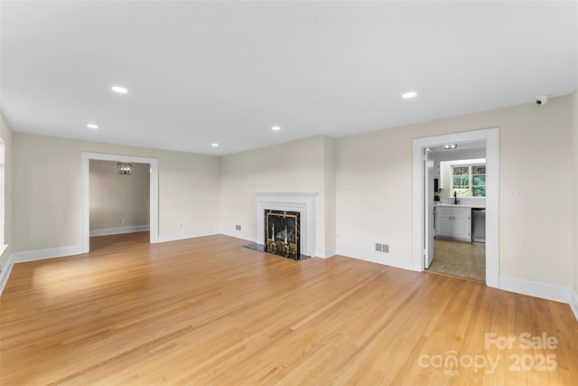 90 Pinewood Rd, Granite Falls, NC 28630 - unfurnished living room featuring light wood-type flooring, a fireplace with raised hearth, recessed lighting, and baseboards