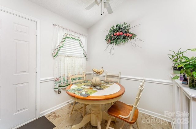 dining room with baseboards, ceiling fan, vaulted ceiling, and a textured ceiling