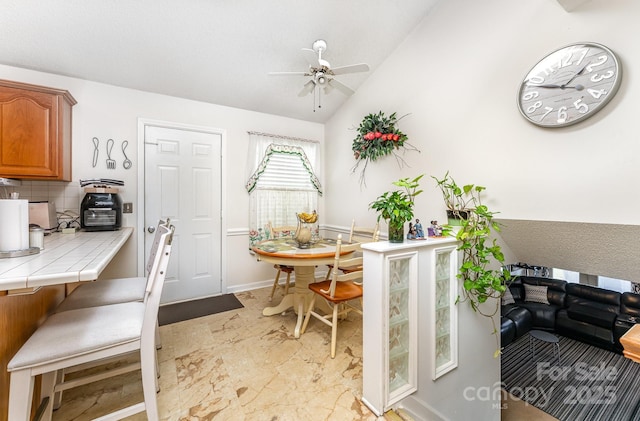 dining space with ceiling fan and vaulted ceiling