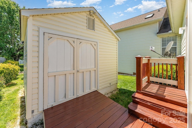 wooden terrace featuring a shed and an outdoor structure