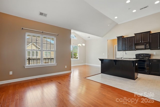 11209 Lazio Ln Unit 1, Charlotte, NC 28277 - kitchen with black appliances, a sink, a chandelier, a kitchen island with sink, and a kitchen breakfast bar