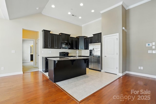 11209 Lazio Ln Unit 1, Charlotte, NC 28277 - kitchen featuring black appliances, dark cabinets, a kitchen bar, a high ceiling, and a kitchen island with sink