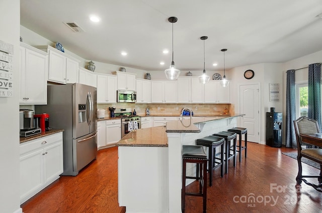 14316 Baytown Ct, Huntersville, NC 28078 - kitchen featuring appliances with stainless steel finishes, dark wood finished floors, white cabinets, a kitchen bar, and decorative backsplash