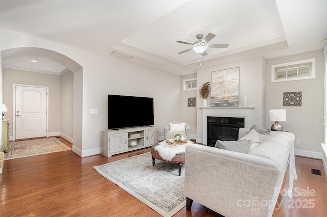 5214 Polo Gate Blvd, Charlotte, NC 28216 - living room featuring arched walkways, a glass covered fireplace, ornamental molding, a ceiling fan, and a raised ceiling