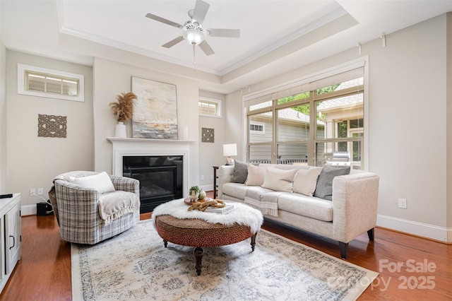 5214 Polo Gate Blvd, Charlotte, NC 28216 - living room featuring a raised ceiling, crown molding, a glass covered fireplace, a ceiling fan, and wood finished floors