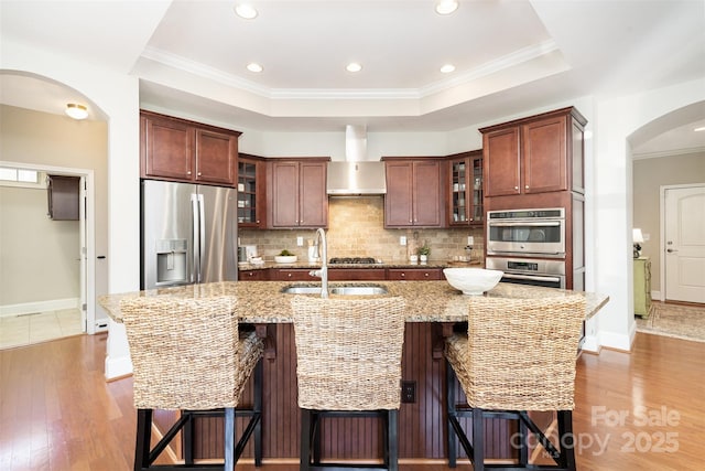 5214 Polo Gate Blvd, Charlotte, NC 28216 - kitchen with stainless steel appliances, wall chimney exhaust hood, tasteful backsplash, ornamental molding, and wood finished floors