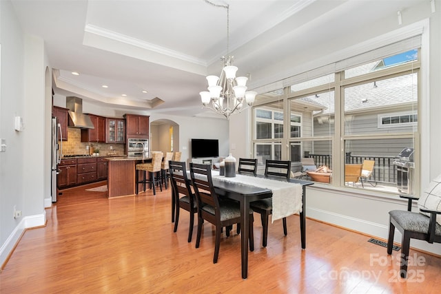 5214 Polo Gate Blvd, Charlotte, NC 28216 - dining space featuring arched walkways, a raised ceiling, crown molding, light wood-type flooring, and a chandelier