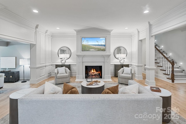 4920 Parview Dr S, Charlotte, NC 28226 - living area with a lit fireplace, light wood-style floors, ornamental molding, a decorative wall, and stairs