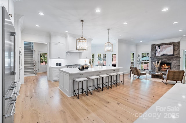 4920 Parview Dr S, Charlotte, NC 28226 - kitchen with crown molding, light wood finished floors, recessed lighting, a stone fireplace, and a kitchen bar