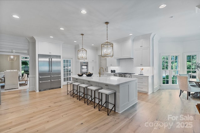 4920 Parview Dr S, Charlotte, NC 28226 - kitchen featuring stainless steel appliances, crown molding, a breakfast bar, light wood-style floors, and white cabinets
