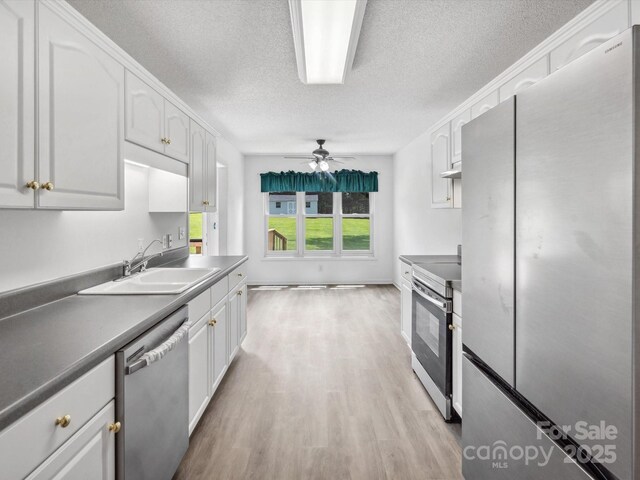 1028 Swaying Oats Dr, York, SC 29745 - kitchen featuring appliances with stainless steel finishes, a sink, white cabinets, a textured ceiling, and light wood-style floors