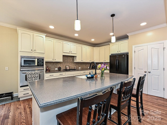 410 Deer Brush Ln, Waxhaw, NC 28173 - kitchen featuring stainless steel appliances, dark countertops, a sink, crown molding, and a breakfast bar