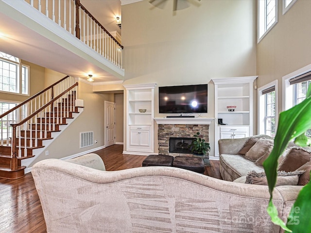 410 Deer Brush Ln, Waxhaw, NC 28173 - living room featuring a towering ceiling, dark wood-type flooring, stairs, a stone fireplace, and baseboards