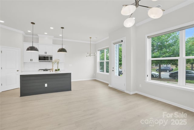 5946 Ardrey Kell Rd, Charlotte, NC 28277 - kitchen with stainless steel microwave, plenty of natural light, white cabinetry, a chandelier, and ornamental molding