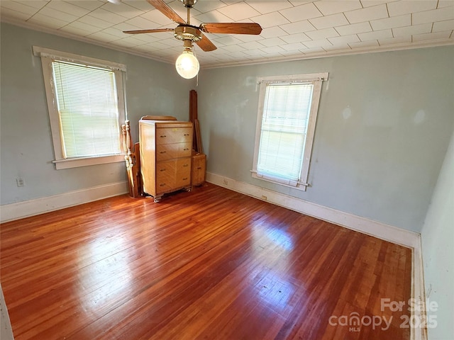 unfurnished room featuring crown molding, wood finished floors, ceiling fan, and baseboards