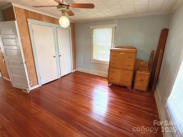 unfurnished bedroom featuring ornamental molding, wood finished floors, baseboards, and a ceiling fan