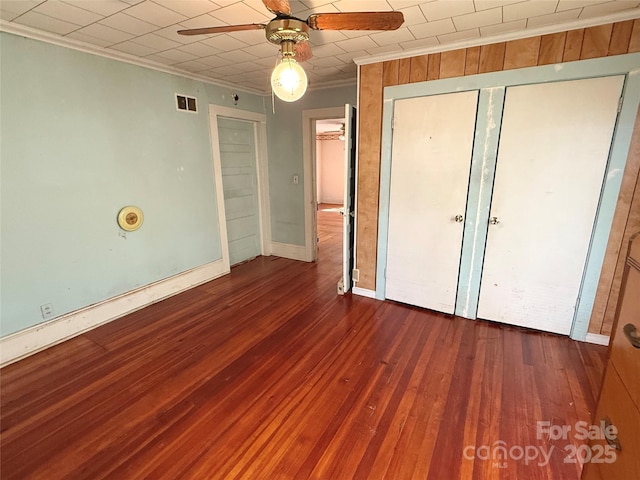 unfurnished bedroom featuring crown molding, wood-type flooring, a ceiling fan, and baseboards