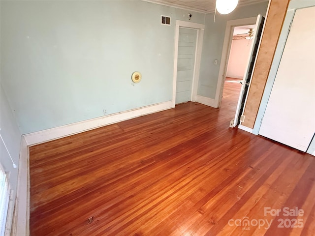 spare room with ornamental molding, wood finished floors, and baseboards