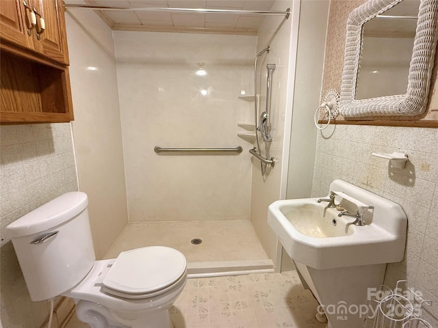 full bathroom with tile walls, toilet, a shower stall, and a sink