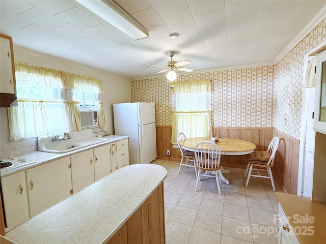 kitchen with white appliances, wallpapered walls, light countertops, crown molding, and wainscoting