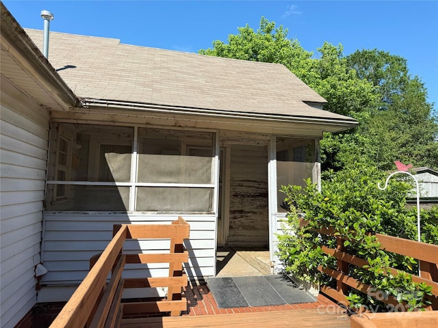 doorway to property featuring roof with shingles