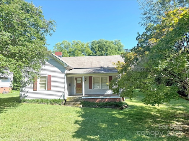 view of front facade with a porch, a front yard, and a chimney