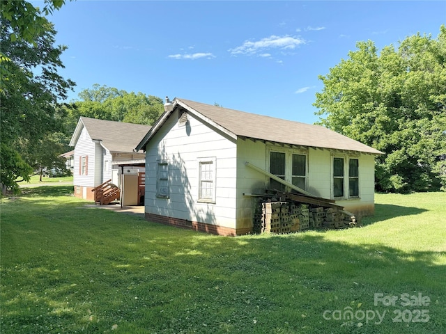 back of house with a yard and a shingled roof