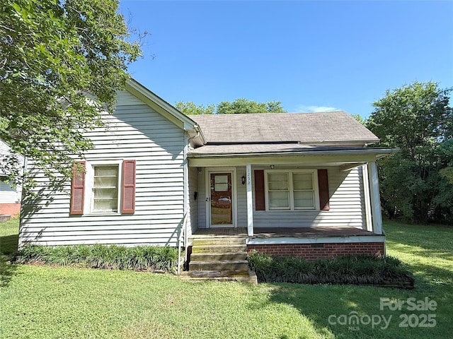 bungalow-style home with a front lawn, a shingled roof, and covered porch