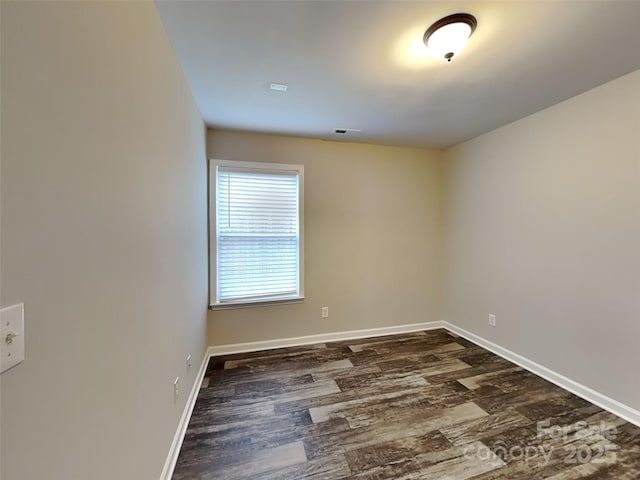 unfurnished room with dark wood-type flooring and baseboards