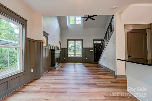 600 S Cline Ave, Newton, NC 28658 - unfurnished living room featuring a decorative wall, ceiling fan, light wood-type flooring, a lit fireplace, and stairs