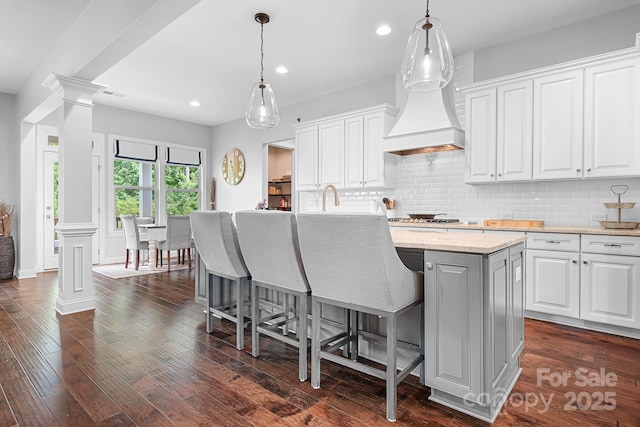 10911 Skymont Dr, Huntersville, NC 28078 - kitchen with an island with sink, decorative columns, backsplash, white cabinets, and recessed lighting