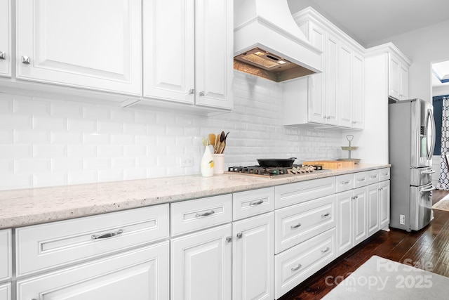 10911 Skymont Dr, Huntersville, NC 28078 - kitchen with appliances with stainless steel finishes, custom exhaust hood, dark wood-style flooring, white cabinetry, and backsplash