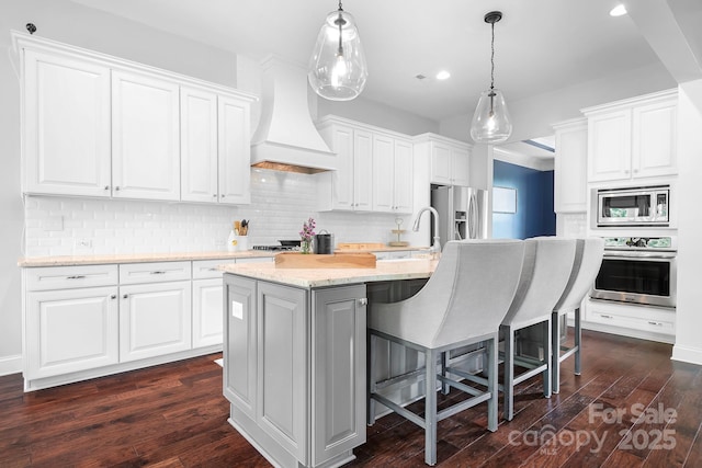 10911 Skymont Dr, Huntersville, NC 28078 - kitchen featuring appliances with stainless steel finishes, a sink, custom range hood, a kitchen island with sink, and dark wood-style floors