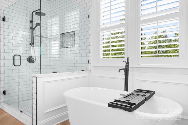 10911 Skymont Dr, Huntersville, NC 28078 - bathroom with a shower stall, healthy amount of natural light, a soaking tub, a decorative wall, and wood finished floors
