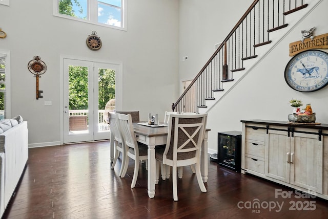 161 Leaning Tower Dr, Mooresville, NC 28117 - dining space featuring a towering ceiling, dark wood-type flooring, baseboards, wine cooler, and stairway
