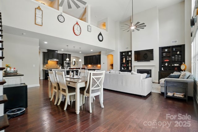 161 Leaning Tower Dr, Mooresville, NC 28117 - dining space with a towering ceiling, a ceiling fan, dark wood finished floors, a fireplace, and baseboards