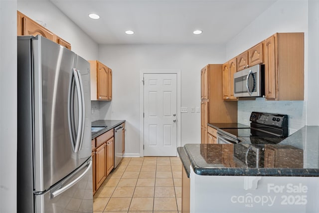 kitchen featuring stainless steel appliances, light tile patterned flooring, dark stone counters, a peninsula, and backsplash