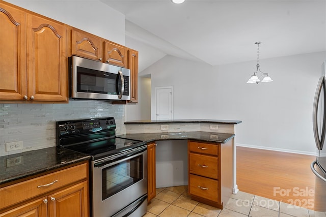 kitchen with appliances with stainless steel finishes, a peninsula, light tile patterned floors, brown cabinetry, and decorative backsplash