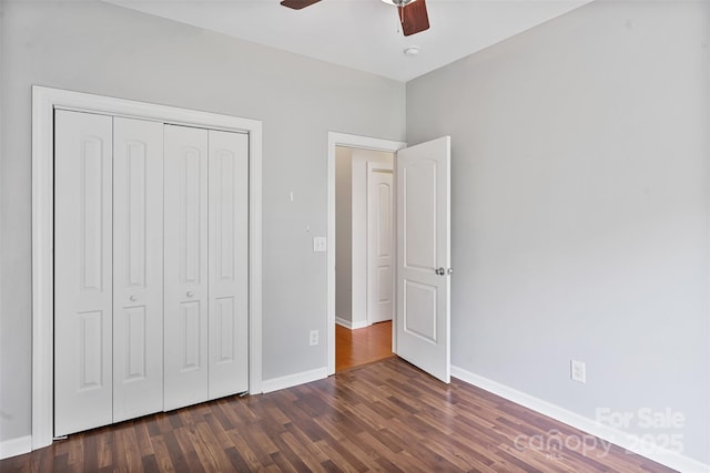 unfurnished bedroom featuring a closet, dark wood-style floors, baseboards, and a ceiling fan
