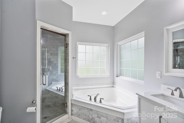 bathroom featuring a shower stall, healthy amount of natural light, a garden tub, and vanity