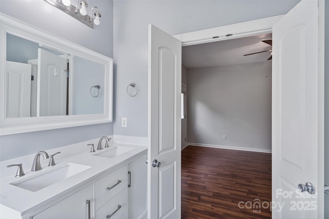 bathroom featuring wood finished floors, double vanity, and baseboards