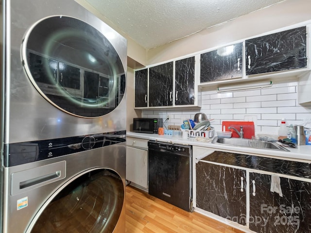 7977 Shady Oak Trl, Charlotte, NC 28210 - kitchen with black appliances, stacked washer / dryer, light wood-style floors, a sink, and light countertops