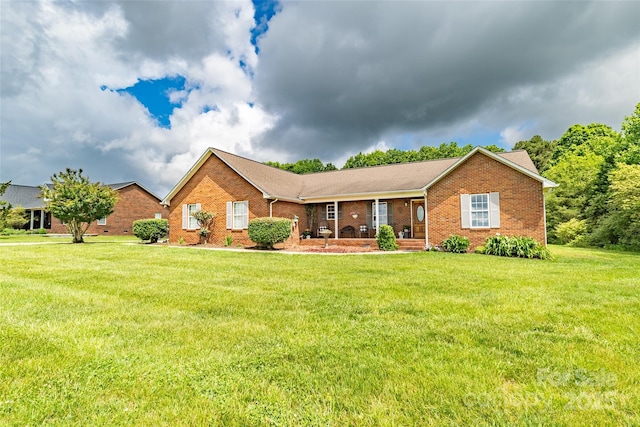 single story home featuring brick siding, covered porch, and a front yard