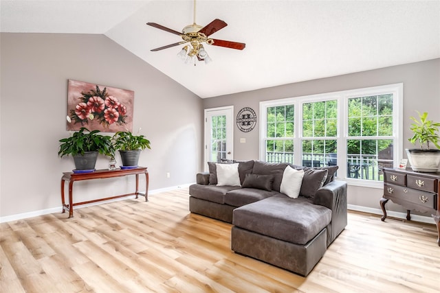 living area with light wood-style floors, a ceiling fan, baseboards, vaulted ceiling, and plenty of natural light