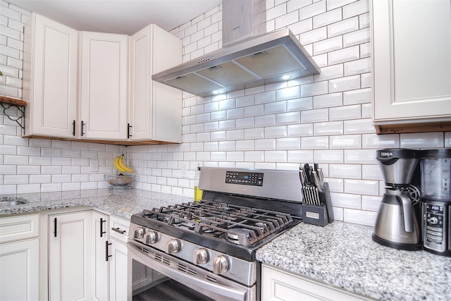 3623 Braden Dr, Charlotte, NC 28216 - kitchen with stainless steel range with gas cooktop, wall chimney range hood, decorative backsplash, white cabinets, and light stone counters