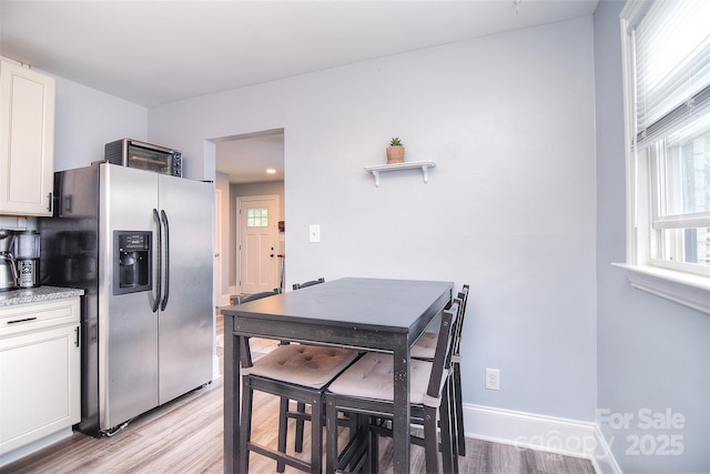 3623 Braden Dr, Charlotte, NC 28216 - kitchen featuring stainless steel fridge with ice dispenser, white cabinetry, light wood finished floors, and baseboards