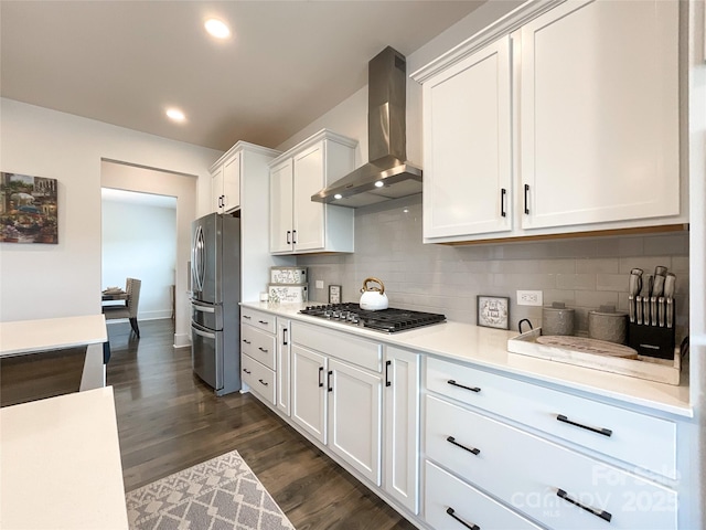 kitchen featuring wall chimney exhaust hood, stainless steel appliances, light countertops, dark wood-type flooring, and white cabinetry