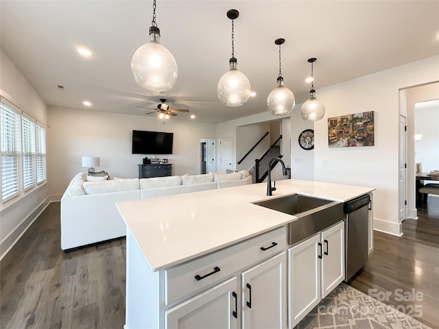 kitchen featuring dishwasher, a sink, dark wood-style flooring, ceiling fan, and baseboards