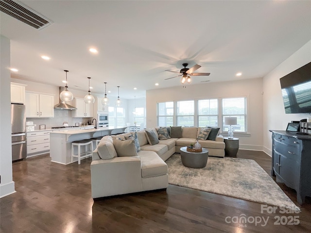 living room with ceiling fan, recessed lighting, dark wood-type flooring, and baseboards